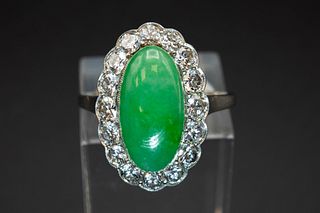 A JADE AND DIAMOND RING, the oval cabochon cut jade set within a surround o