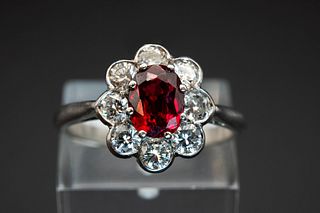 A THAI RUBY AND DIAMOND CLUSTER RING, the oval cut ruby set within a surrou