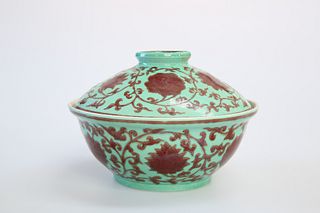 A CHINESE PORCELAIN COVERED BOWL, painted with scrolling foliage on a green