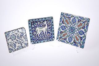 THREE IZNIK POLYCHROME POTTERY TILES, two with floral decoration, the third