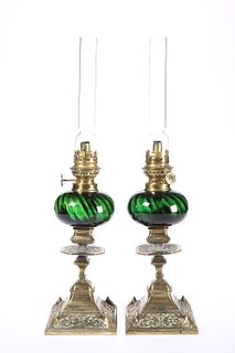 A PAIR OF LATE VICTORIAN BRASS AND GREEN GLASS OIL LAMPS, with scroll cast 