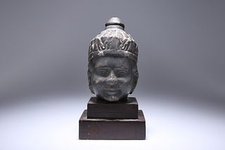 A CARVED STONE HEAD OF A BOY, POSSIBLY TIBETAN, depicted in elaborate headd
