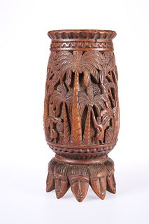 A SOUTH-EAST ASIAN CARVED VESSEL, the base carved as a series of masks. 28.