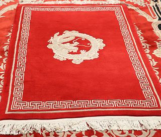 A CHINESE RUG, centred by a dragon, on a red ground. 204cm by 122cm