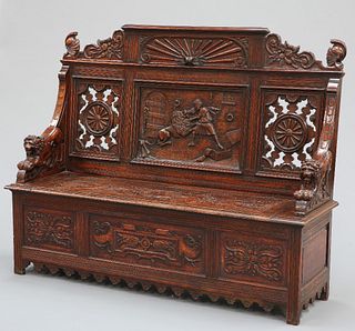 A LATE 19TH CENTURY CARVED OAK SETTLE, the crest centred by a panel carved 