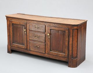 A GEORGIAN OAK DRESSER BASE, with three graduated drawers, fitted with bras