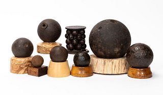 EIGHT CANNONBALLS ON CARVED WOODEN STANDS
