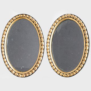 Pair of Small English Ebonized and Parcel-Gilt Oval Mirrors