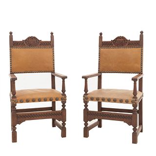 Par de sillones. Francia. Siglo XX. Estilo Enrique II. En talla de madera de roble. Con respaldos semiabiertos y asientos tipo piel.
