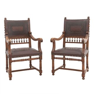 Par de sillones. Francia. Siglo XX. Estilo Enrique II. En talla de madera de nogal. Con respaldos semiabiertos y asientos tipo piel.