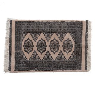 Tapete. Pakistán. Siglo XX. Estilo Boukhara. Anudado a mano en fibras de lana. Decorado con elementos geométricos. 94 x 62 cm.