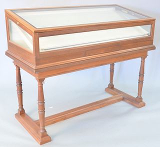 Mahogany showcase with lift top and tilting interior on trestle foot base, 47 1/2" h. x 58" w. x 26 1/2" d.