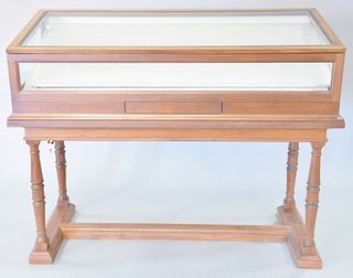 Mahogany showcase with lift top and tilting interior on trestle foot base, 47 1/2" h. x 58" w. x 26 1/2" d.