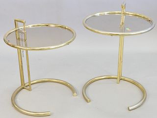 Pair Eileen Gray style adjustable tables, tubular gold tone steel, round glass top, light wear and surface scratches, each 30 1/4" x 20".