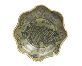 A CHINESE CELADON GLAZED BOWL, with undulating rim, painted with a qilin, b