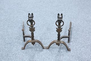 A PAIR OF WROUGHT IRON FIRE DOGS, each beast cast holding a loop in its mou