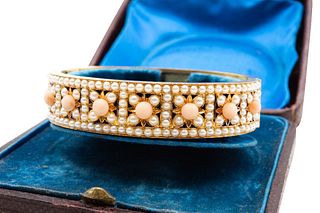 A LATE 19TH CENTURY CORAL AND HALF PEARL BANGLE
 The hinged bangle formed f