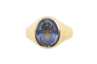 A SAPPHIRE INTAGLIO RING
 The oval plaque incised with a crest, in a polish