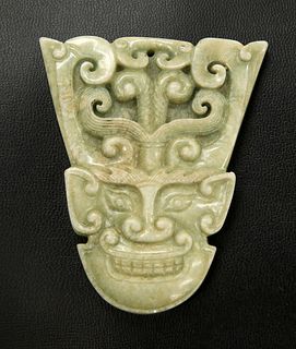 A CHINESE JADE PENDANT, carved with a mask. 7.6cm by 6.4cm