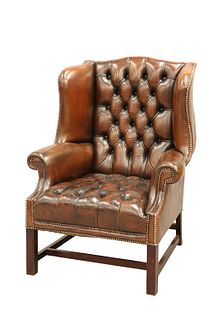 A HANDSOME DEEP-BUTTONED BROWN LEATHER WING CHAIR, with buttoned back and s