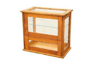 AN OAK COUNTER-TOP DISPLAY CABINET, with two glass shelves and hinged door.
