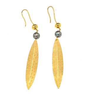 Par de aretes con dos perlas en oro amarillo de 18k. Diseño de hoja. 2 perlas color negro con sobretono color verde de 9 mm.