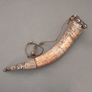 Instrumento musical. Camerún, Siglo XX. Grupo étnico Bamileke. Cuerno tallado, conchas de cauri y fibras naturales. 49 x 8.5 cm