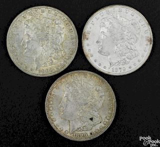 Three Morgan silver dollars, to include an 1879 S, UNC, an 1890, AU, and a 1902 O, UNC.