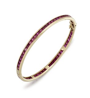 A RUBY BANGLE
 The hinged bangle, set with a conti