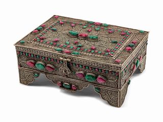 A Ruby and Emerald-Encrusted Silvered Metal Filigree Casket
Height 5 x length 11 1/2 x depth 8 1/2 inches.