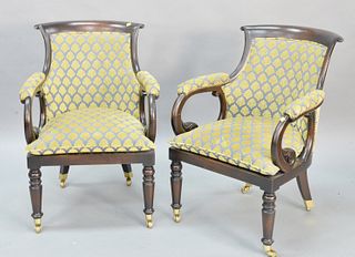 Pair of upholstered armchairs having brass casters.