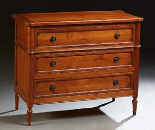 French Provincial Louis XVI Style Carved Cherry Commode, 20th c., the shaped stepped top over three drawers flanked by reeded round...