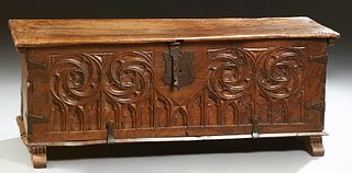 French Gothic Carved Walnut Coffer, 19th c., the lifting lid with iron strap hinges, corner braces and lock, over a front panel with...
