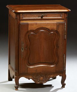 French Louis XV Style Carved Walnut Nightstand, c. 1860, the stepped rounded corner top above a frieze drawer and an arched fielded...
