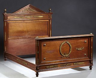 French Ormolu Mounted Carved Mahogany Empire Style Bed, c. 1900, with a peaked headboard flanked by ormolu finials, to wooden rails...