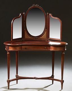 French Louis XVI Style Carved Walnut Dressing Table, early 20th c., the oval beveled mirror flanked by two hinged arched beveled mir...