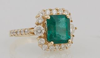 Lady's 14K Yellow Gold Dinner Ring with a 3.1 carat emerald, atop a border of round diamonds, the shoulders of the band also mounted...
