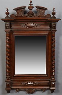 French Henri II Style Carved Walnut Overmantel Mirror, c. 1880, the broken arch crest with a center turned finial, flanked by turned...