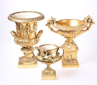 THREE GILT COMPOSITION URNS, each with twin handl