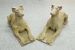 A PAIR OF WEATHERED CARVED STONE MODELS OF RECUMBENT HOUNDS