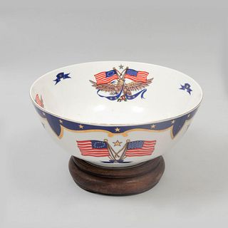 Bowl conmemorativo. Estados Unidos. Siglo XX. Elaborado en cerámica con base de madera. Decorado con águila y bandera. 23 cm diámetro