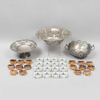 Lote de centros de mesa y servilleteros. Italia y China. Siglo XX.  Elaborados en pewter, porcelana Crown Baccara y metal plateado.