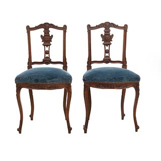Par de sillas. Francia. Siglo XX. Estilo Luis XV. En talla de madera de nogal. Con respaldos semiabiertos y asientos en tapicería azul.