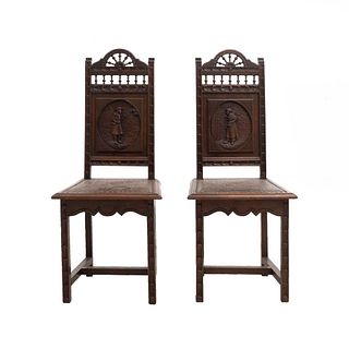 Par de sillas. Francia. Siglo XX. Estilo Bretón. En talla de madera de roble. Con respaldos semiabiertos y asientos tipo piel.