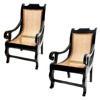 Par de sillones. Siglo XX. En talla de madera ebonizada. Con respaldos y asientos de bejuco.