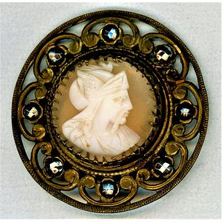 A CARVED HELMET SHELL CAMEO BUTTON IN AN ORNATE SETTING