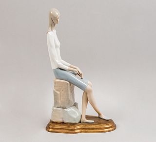 Mujer con libro. Siglo XX. Elaborada en porcelana. Acabado brillante. Con base de madera dorada. 40 cm de alto.