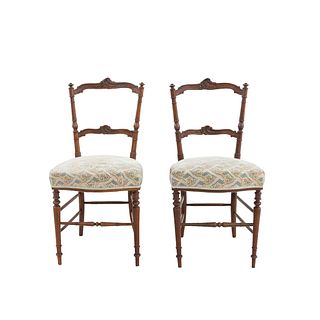 Par de sillas. Francia. Siglo XX. Estilo Enrique II. En talla de madera de nogal. Con respaldos escalonados y asientos en tapicería.