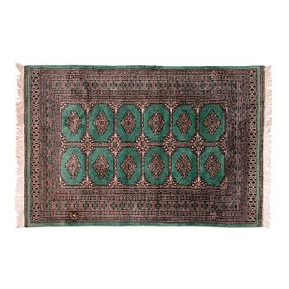 Tapete. Siglo XX. Estilo Bokhara. Elaborado en fibras de lana y algodón. Decorado con motivos geométricos sobre fondo verde.