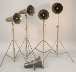 Five WWII era loudspeakers, four having tripod stands.